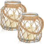 Two clear glass nautical lanterns with jute rope handles and flickering LED candles inside, on a tabletop.