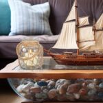 Two clear glass nautical lanterns with jute rope handles and flickering LED candles inside, on a tabletop.