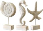 Set of three white hand-carved wooden coastal figurines: a starfish, a conch shell, and a seahorse, displayed on a tabletop.