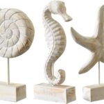 Set of three white hand-carved wooden coastal figurines: a starfish, a conch shell, and a seahorse, displayed on a tabletop.