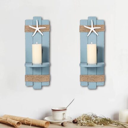 Two blue wooden starfish wall candle sconces with hemp rope accents, holding small candles, mounted against a light wall.